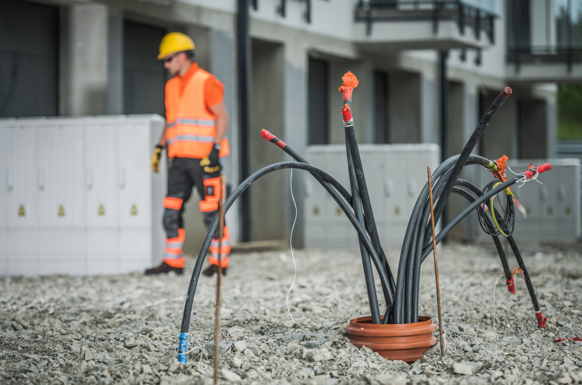 Arbeiter an Kabel-Leerrohren für den Glasfaser-Hausanschluss vor einem Gebäude