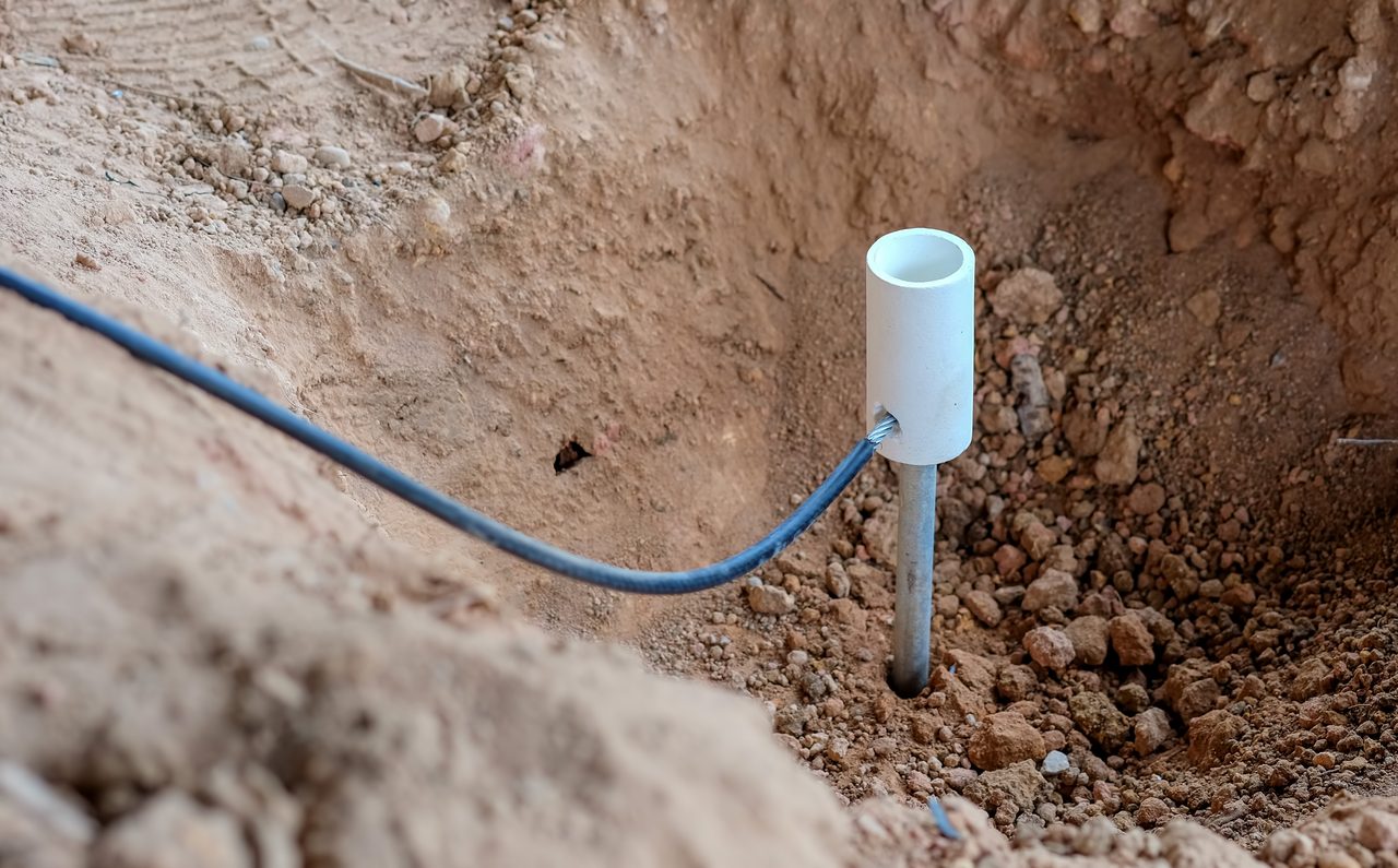 Kabel und Erdungsstab in einer Baugrube beim Kabeltiefbau