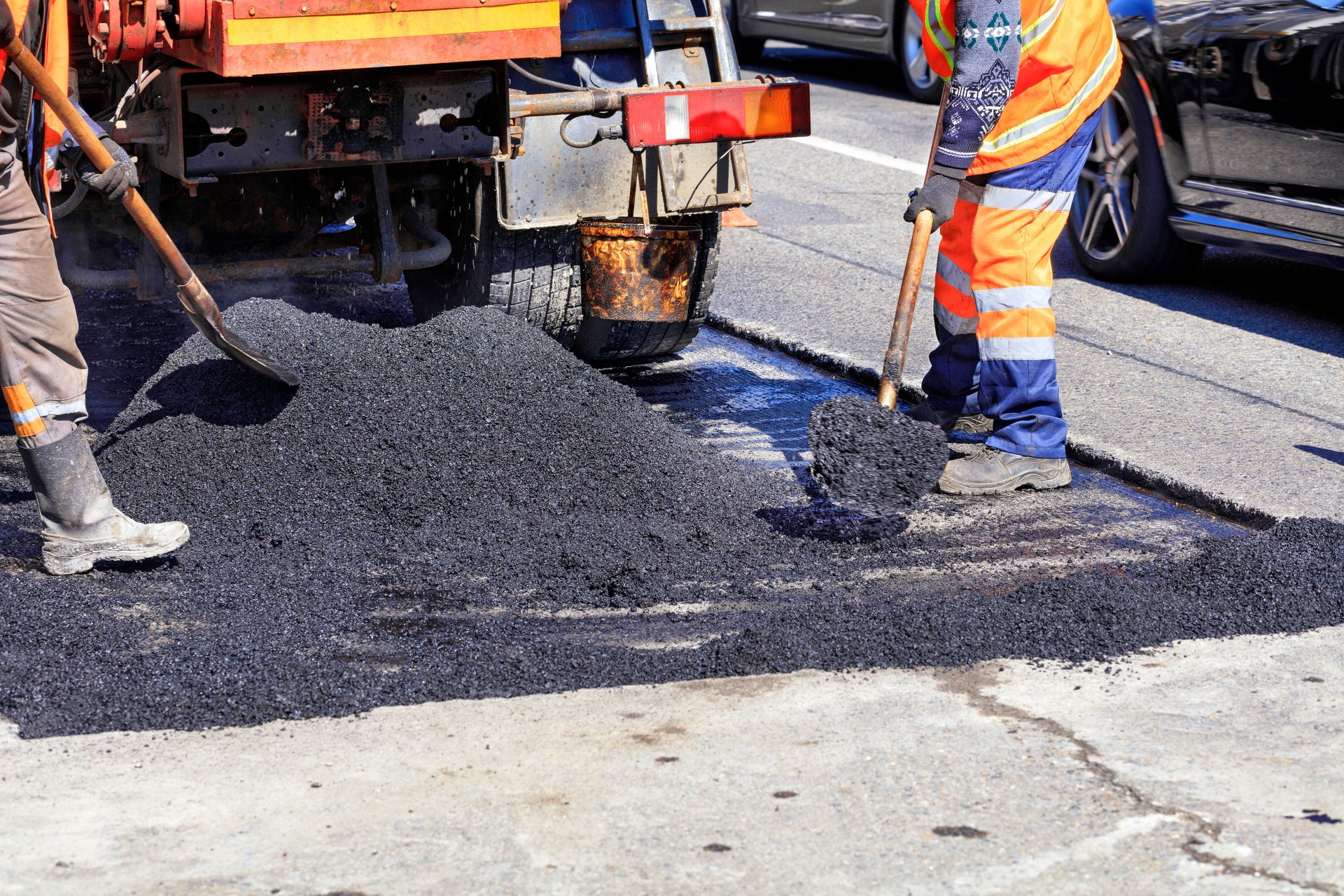 Straßenbauer verteilt frischen Asphalt beim Einbau einer Fahrbahn