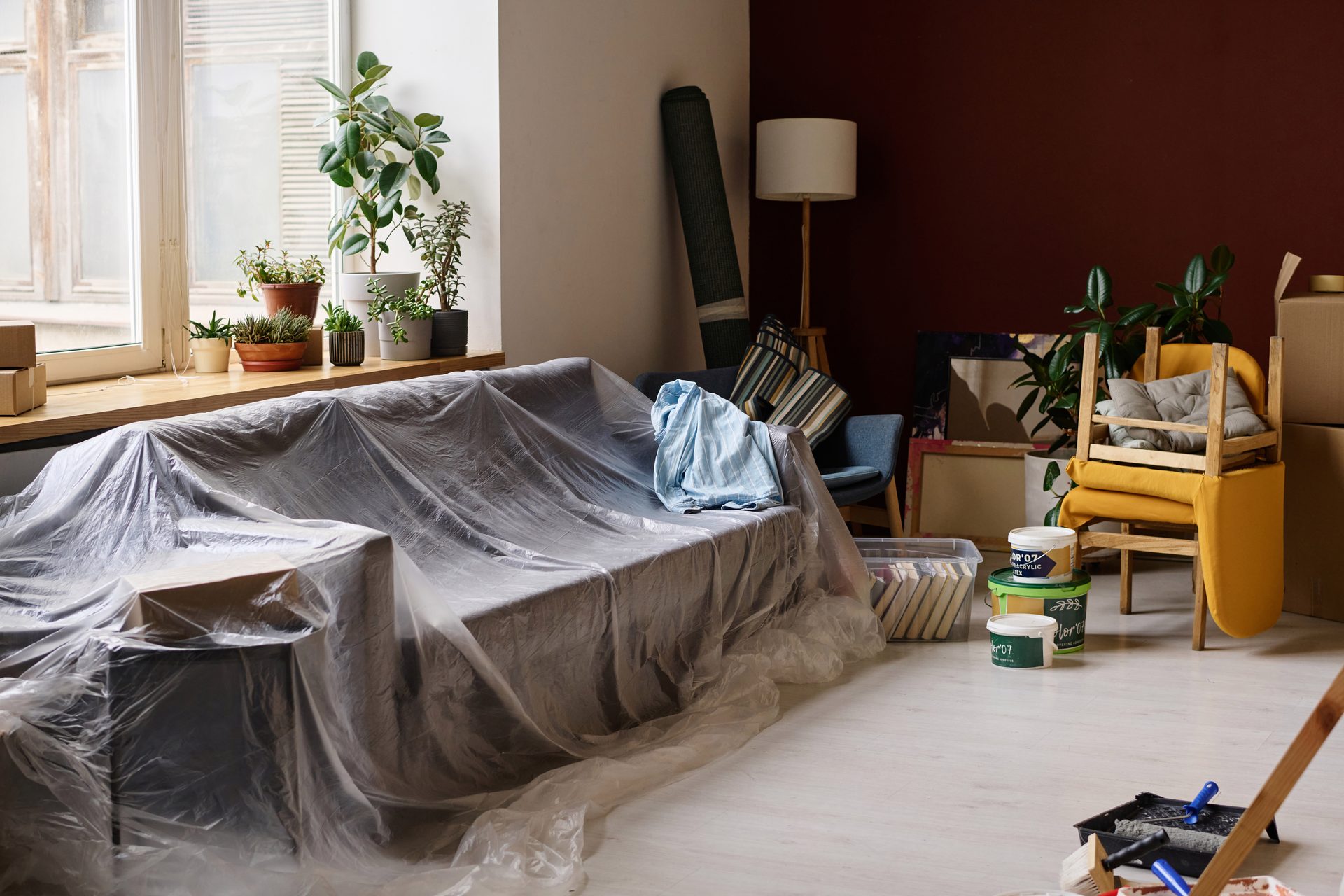 Mit Folie abgedeckte Möbel und Umzugskartons bei der Wohnungsrenovierung
