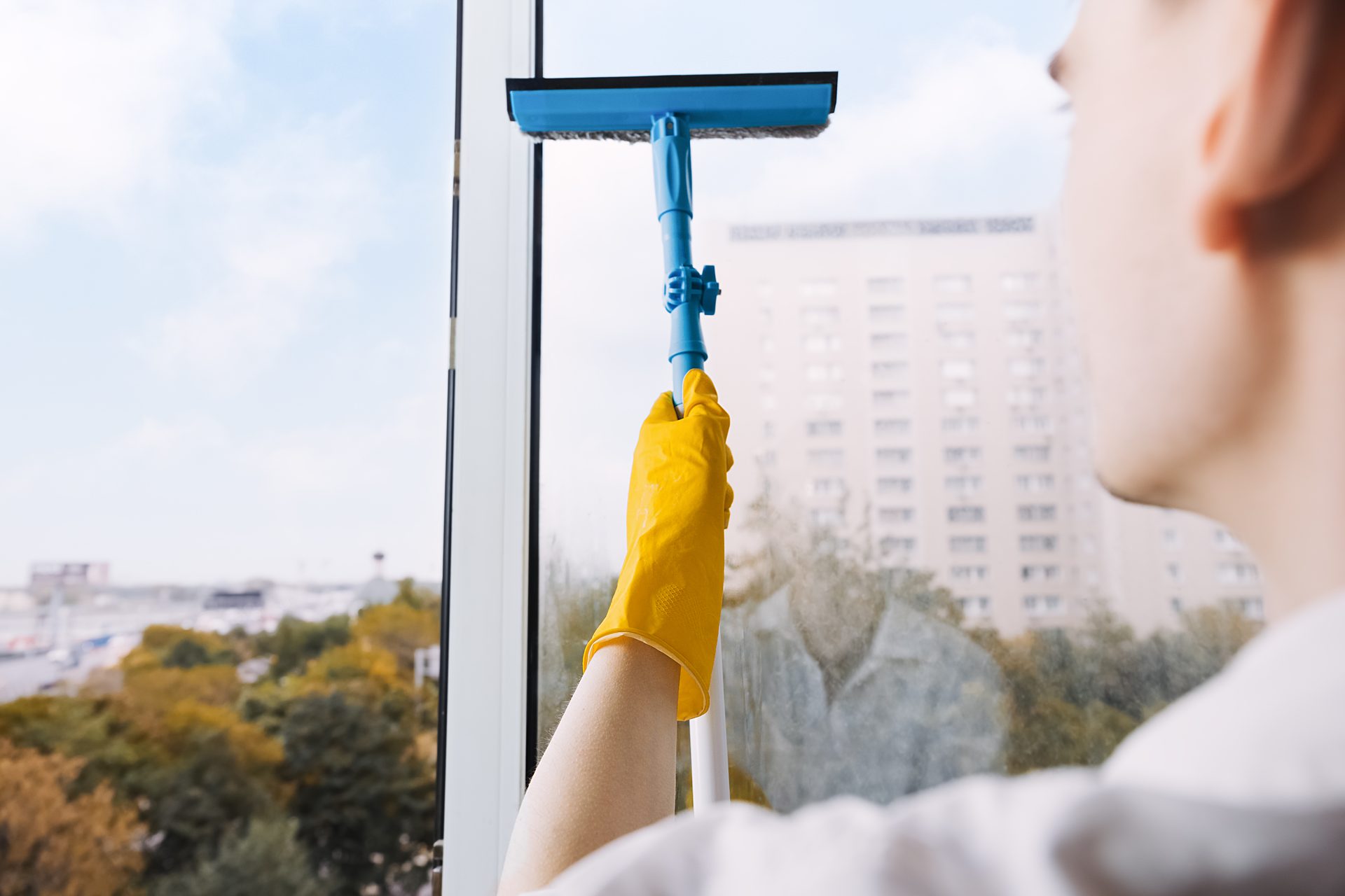 Glasreinigung eines Fensters mit Abzieher und Handschuhen