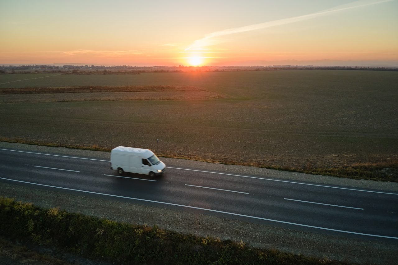 Transporter fährt bei Sonnenaufgang über die Autobahn – Direktfahrt und Express