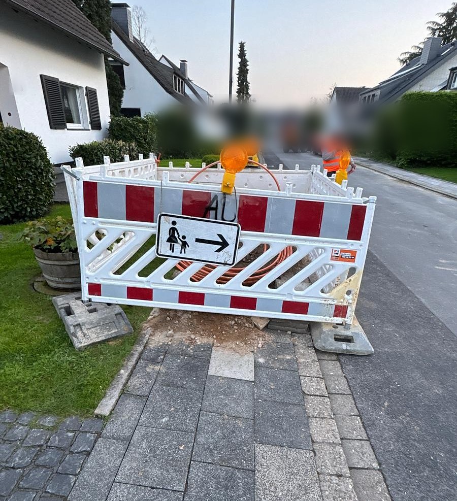 Normgerechte Baustellensicherung mit Gehwegsperrung und Warnleuchten am Glasfaser-Hausanschluss