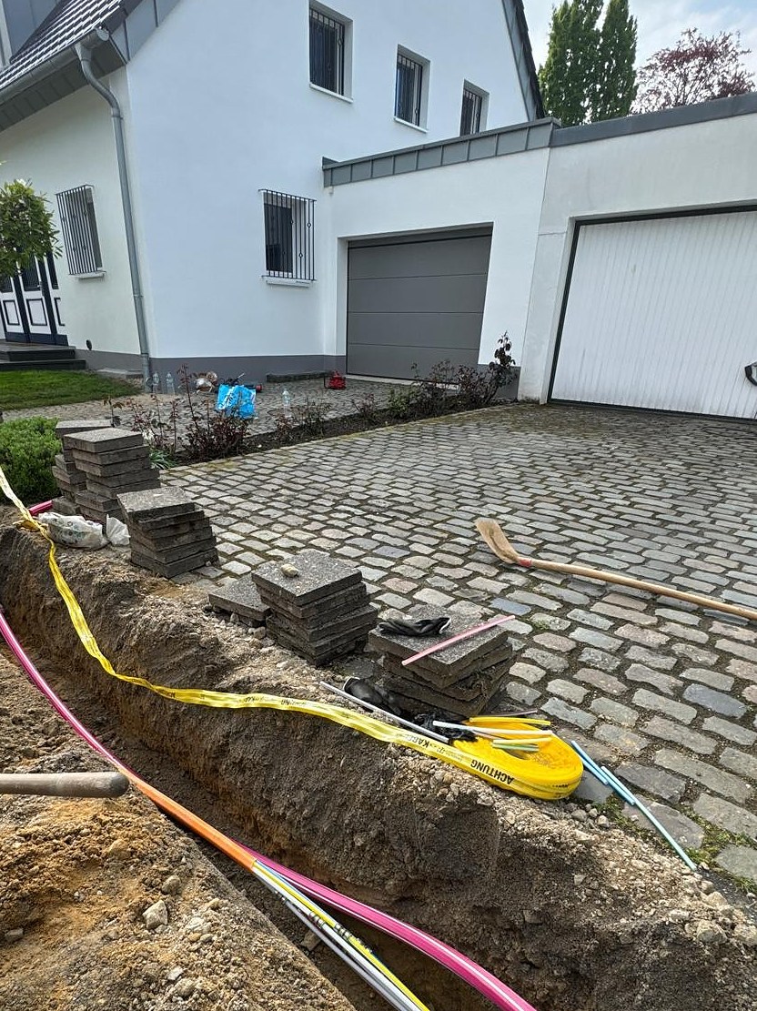Mikrorohrverlegung mit Trassenwarnband entlang der gepflasterten Hofeinfahrt