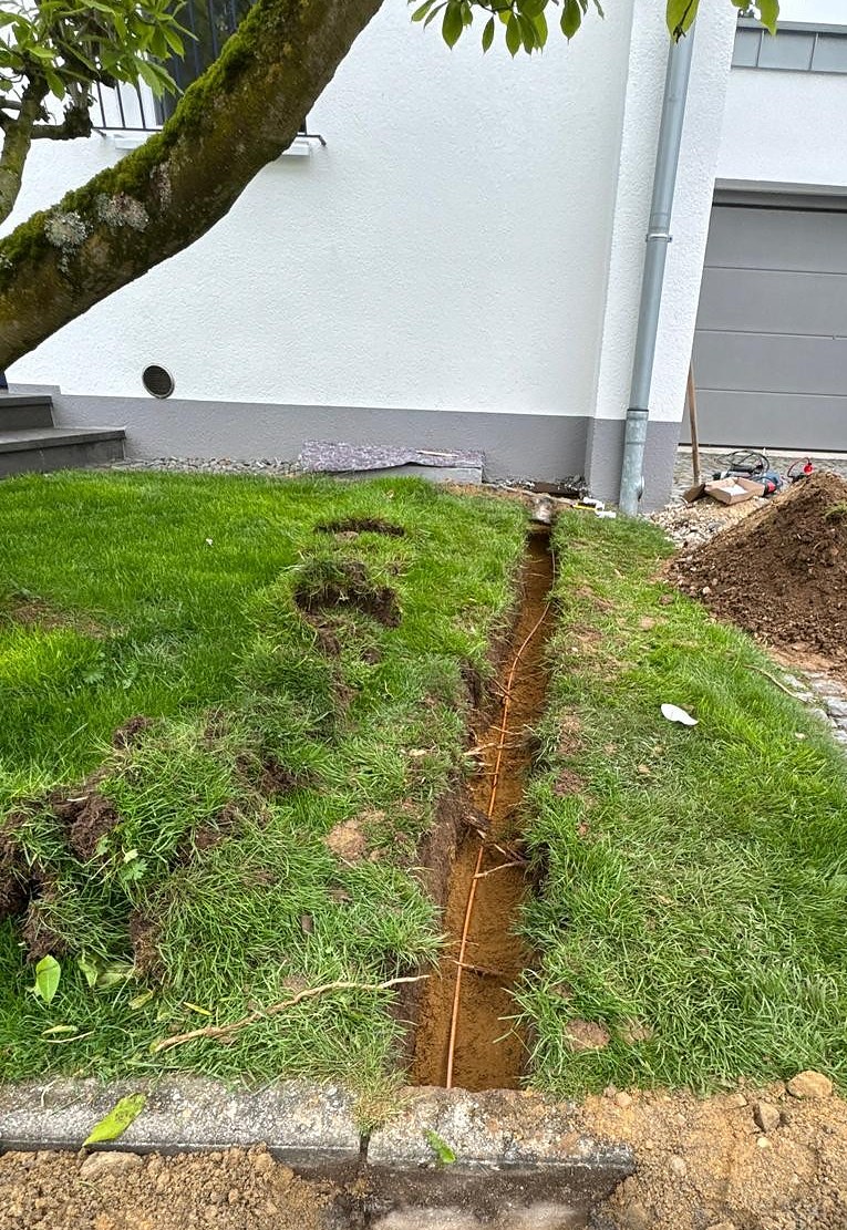 Schmaler Leitungsgraben für das Glasfaser-Mikrorohr im Rasenbereich des Vorgartens